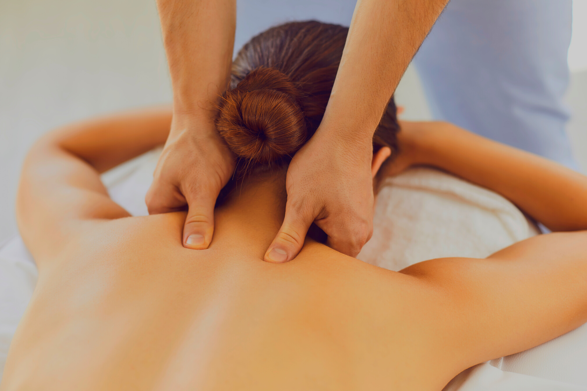 Men's Hands Do a Therapeutic Neck Massage for a Girl Lying on a Massage Couch in a Massage Spa.